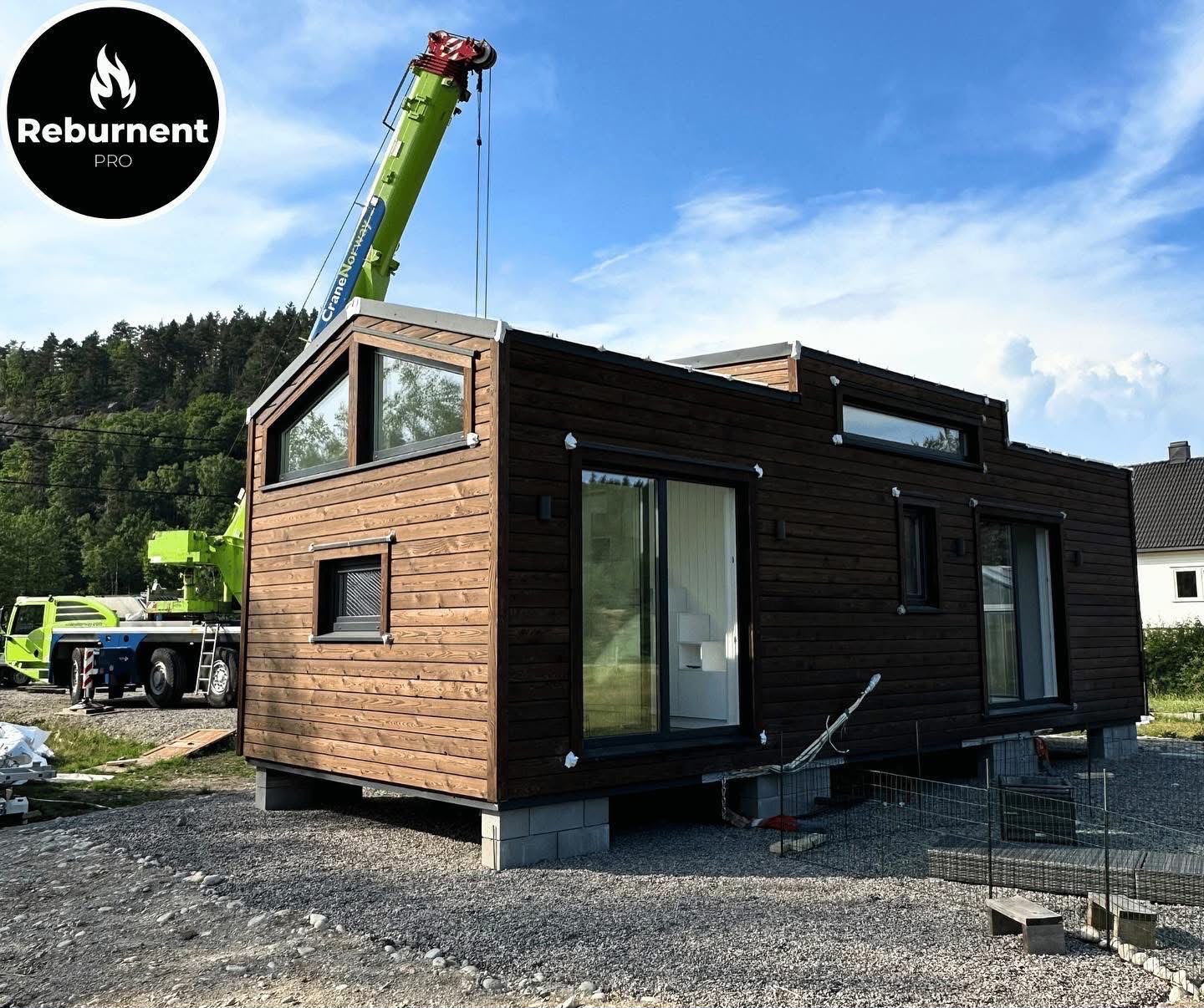 Modular house with charred cladding being set by crane